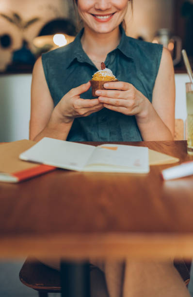 istock Anonymous Smiling Female Student Making a Short Study Break to Enjoy a Delicious Pumpkin Spice Cupcake 1286034592