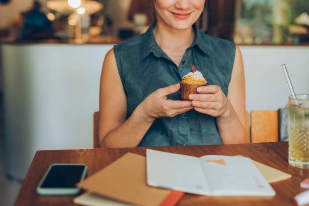 istock Anonymous Smiling Female Student Making a Short Study Break to Enjoy a Delicious Pumpkin Spice Cupcake 1286034594
