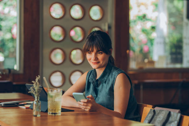 istock Telecommuting: Pretty Brunette Businesswoman Working Remotely from a Local Cafe while using her Tablet PC and her Mobile Phone 1286034598