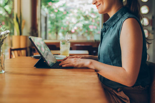 istock Telecommuting: Anonymous Young Businesswoman Working Remotely on her Tablet PC from a Cozy Cafe 1286034618