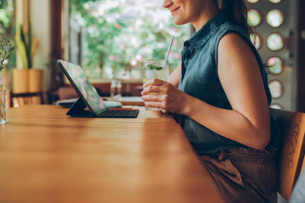 istock Telecommuting: Anonymous Young Businesswoman Joining an Online Video Call while Having a Drink at a Coffe House 1286034631