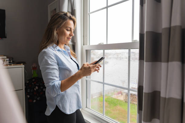 istock Woman texting on cellphone at home by the window 1286035327