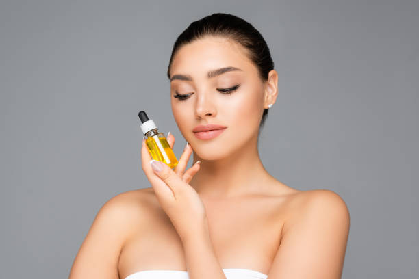 istock woman holding bottle with serum isolated on grey 1286044328