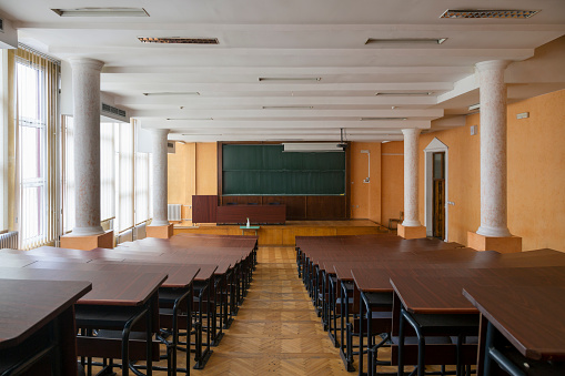 Green clean board with projection screen in classroom without people and empty wooden benches in covid- 19 time