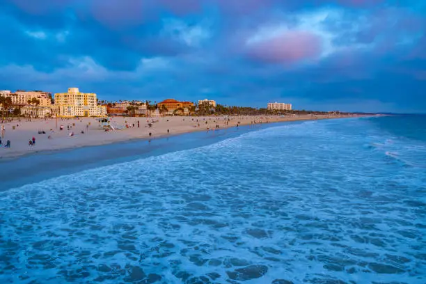 Blue hour sunset on crowded Santa Monica Beach in California. Popular peaceful outdoor recreation location for families, locals and tourists. American west coast landscape/ seascape weekend setting.