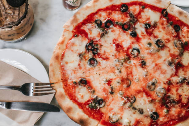 Pizza with Mozzarella cheese, ham, pepper,Tomatoes, and olives. Having party at home, eating pizza and having fun. leisure, food and drinks, people and holidays concept