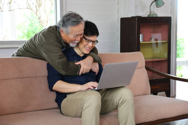istock Senior Asian man in retirement age hugging his son from behind while he is working from home using laptop 1286052411