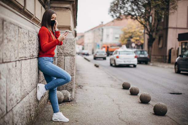 istock Woman with protective face mask using smart phone on the street 1286055131