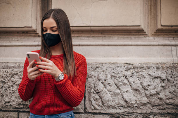 istock Woman with protective face mask using smart phone on the street 1286055977