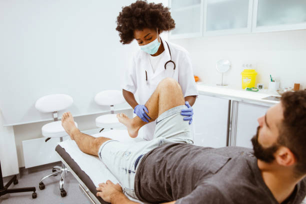 an orthopedic doctor examines the injured patient's leg - orthopedics imagens e fotografias de stock