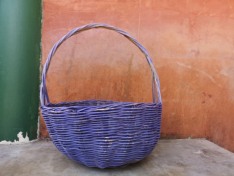 Blue rattan basket on gray concrete table, orange and green  color painting on surface mortar wall texture cement plaster masory man's work