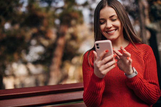 istock Beautiful woman using smart phone in public park 1286066590