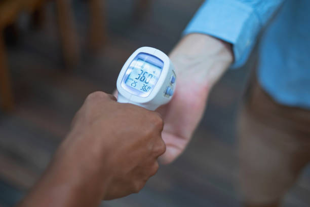 Unrecognizable waiter measuring customer body temperature from his wrist