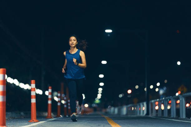 Asian woman practicing running at night stock photo