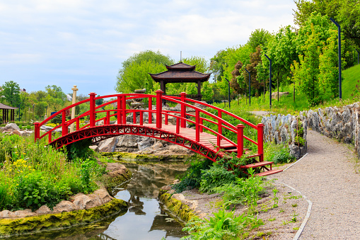 Red bridge and gazebo by a pond in Japanese garden