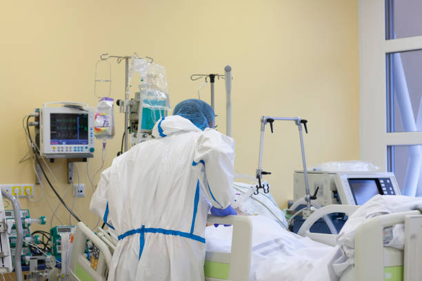 The nurse is talking with  a patient who fell ill with a new type of coronavirus covid-19. Male nurse with protective coverall clothing in intensive care unit in hospital. stock photo