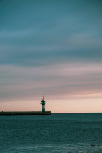 istock at the end of harbour wall there is a green-white lighthouse 1286077715