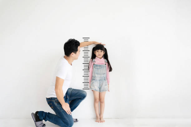 pai mede crescimento de sua filha filho em parede de tijolos brancos em branco - measuring child instrument of measurement wall - fotografias e filmes do acervo