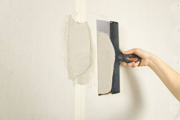 istock Woman putty plaster. Builder female indoor worker plastering wall with spatula trowel tool. 1286082714