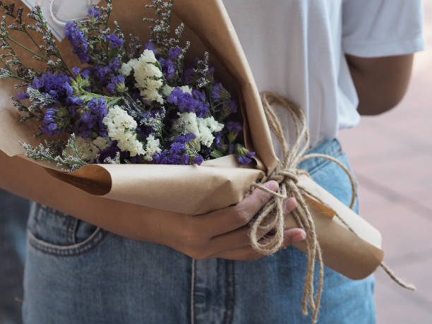 statique, lavande de mer, romarin de marais, couleur blanche et pourpre un bouquet de fleurs dans une main de femme - small bouquet photos et images de collection