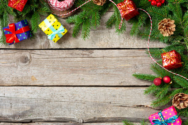 istock Christmas background with gift boxes Packed in different colors on a brown wooden table. Christmas or new year gifts under the fir branches. The view from the top. Copyspace 1286094213