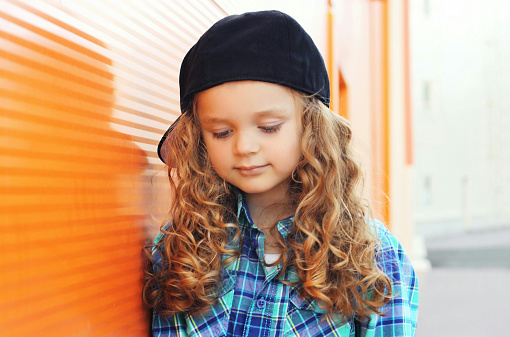 Portrait of little girl child wearing a baseball cap in the city