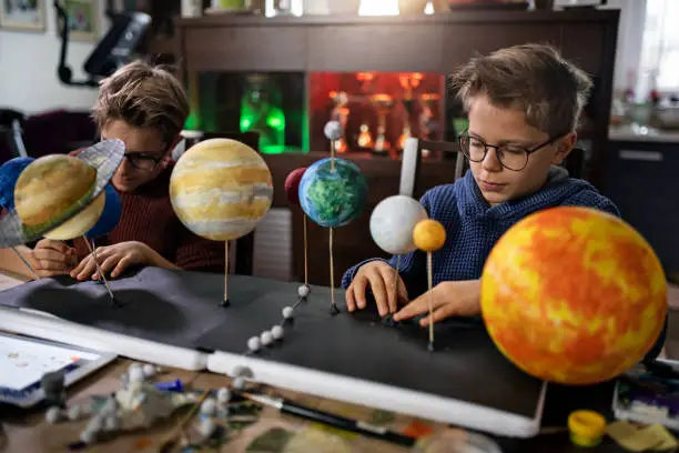 Little boys making solar system project at home.
The boys are attaching sun and planets on sticks to the stand.
Shot with Canon R5