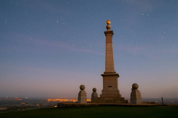 Stars twinkle over a memorial to the Boer War on Coombe Hill, in the Chiltern Hills in Buckinghamshire. In the distance is the the town of Aylesbury. Composite image.