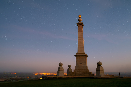 Stars twinkle over a memorial to the Boer War on Coombe Hill, in the Chiltern Hills in Buckinghamshire. In the distance is the the town of Aylesbury. Composite image.