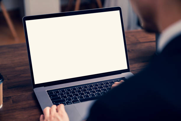 istock Laptop a blank screen on the table for putting on a computer advertisement. Man holding a coffee cup in hand and sitting at desk in an office. 1286100306