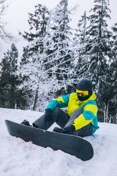 istock man sitting on snowed ground with snowboard 1286102125