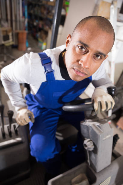 istock Closeup face of confident hispanic warehouse worker driving forklift 1286103381