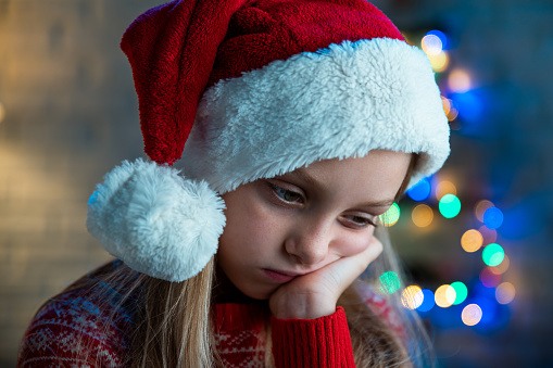 Sad girl wearing Santa's hat. Coronavirus quarantine concept.