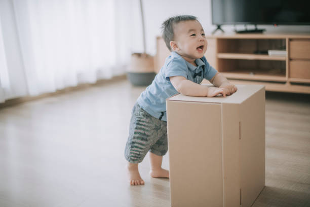彼の親を見てリビングルームでカートンボックスで遊んで笑う幸せなアジアの中国の赤ちゃんの男の子 - living room learning healthy lifestyle one person ストックフォトと画像
