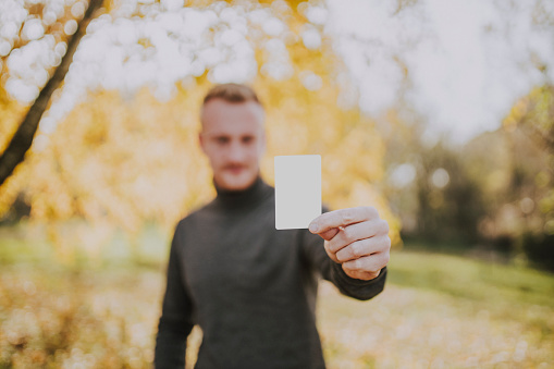 Close up of man holding white empty card