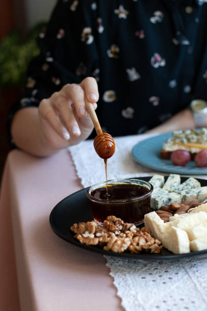 istock A gourmet lunch: a black plate of appetizers on a white tablecloth: walnuts, almonds, cheese, roquefort cheese, a small bowl of honey, a slice of rye bread with roquefort and cream cheese, a bowl of sweet juicy fruits. A white tablecloth background. 1286111469