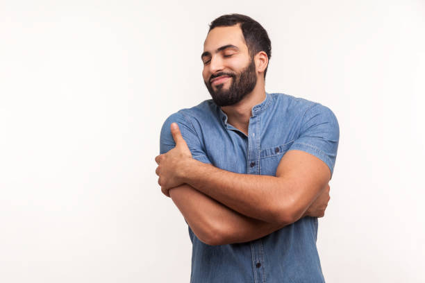 uomo narcisista egoista con la barba che si abbraccia, conforta e sostiene, soddisfa i suoi bisogni di sentire felicità, autostima - solo un uomo foto e immagini stock