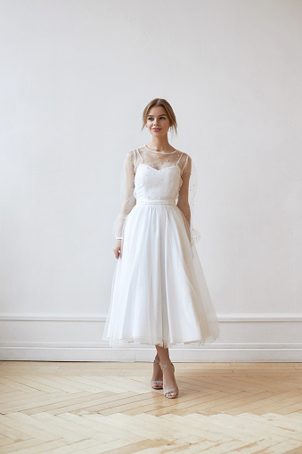 Beautiful slender woman in white wedding dress, new collection of dresses for the bride. Noise, out of focus