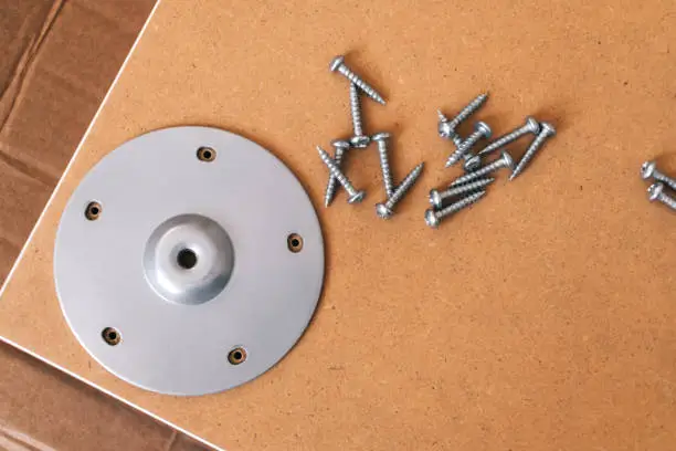 Photo of Furniture assembly concept, fixing plate and screws on wooden table