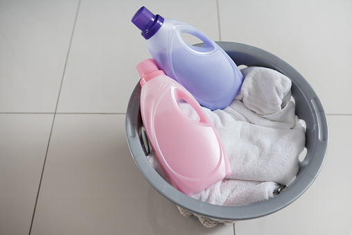 High angle shot of a washing basket filled with clean laundry and two bottles of fabric softener