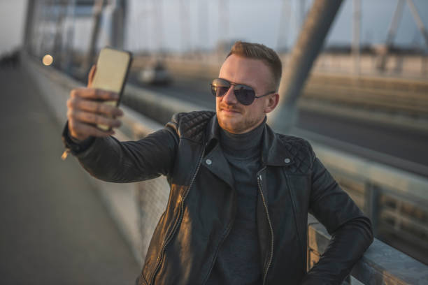 istock Fashionable man using taking a selfie by his smart phone 1286117582