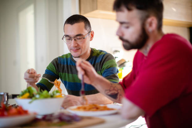 istock Young man picking up spaghetti with a fork, having lunch with boyfriend at home 1286118768