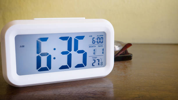 istock The white alarm clock digital numbers on wood table. 1286118922