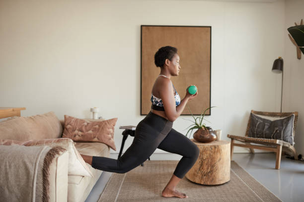 Be stronger than your excuses Shot of a young woman exercising at home lunge stock pictures, royalty-free photos & images