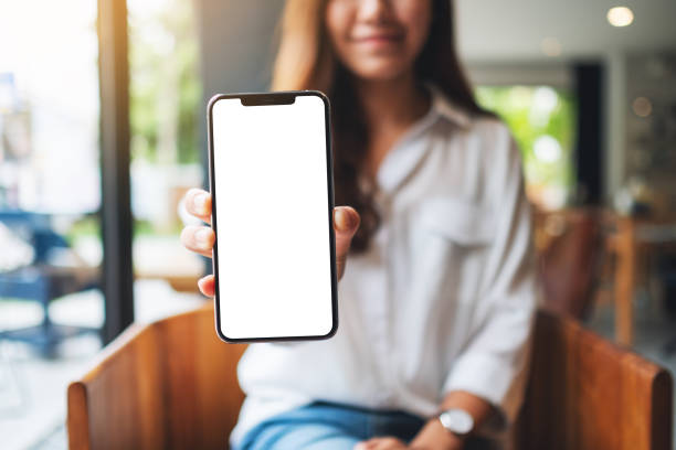 istock a woman holding and showing mobile phone with blank white screen 1286120194