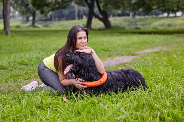 istock Girl hugs black long-haired dog while walking in park. 1286123241