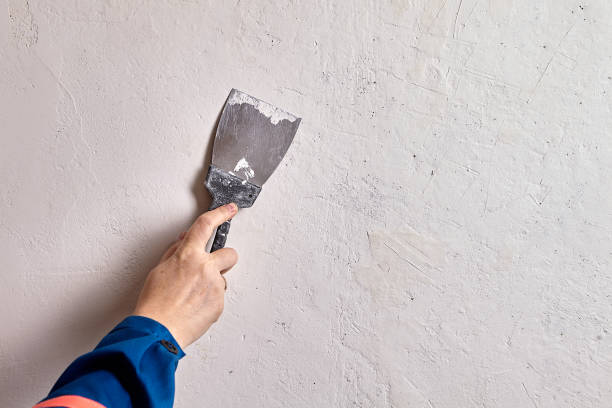 plasterer is applying finishing plaster using a steel putty knife or spatula. - plasterer plaster wall dirty imagens e fotografias de stock