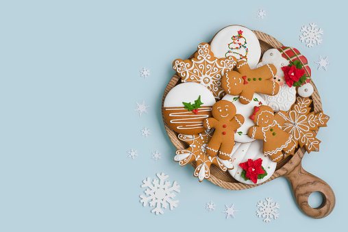 Wooden plate with Christmas homemade gingerbread cookies on blue background