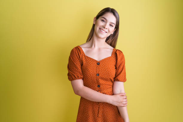 Lovely young woman standing and smiling at camera A lovely young latin woman standing, holding her arm and smiling at the camera. medium shot stock pictures, royalty-free photos & images