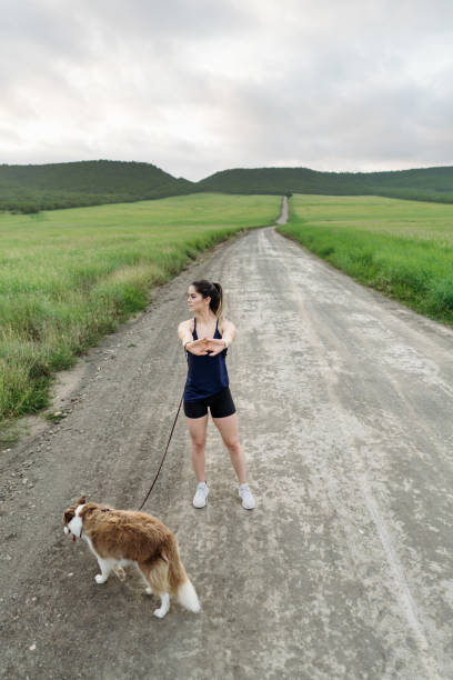 istock Young sportswoman standing on road with dog 1286129572